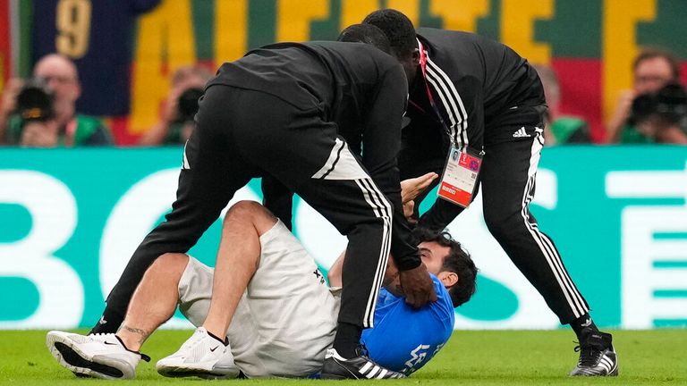 Seorang penyusup tertangkap berlari melintasi lapangan dengan bendera pelangi selama pertandingan sepak bola Grup H Piala Dunia antara Portugal dan Uruguay di Stadion Lusail di Lusail, Qatar Senin 28 November 2022.  (AP Photo/Themba Hadebe)