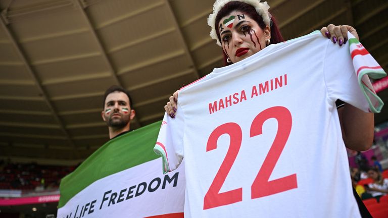 Iranian fans hold up a t-shirt and flag with protest slogans at today&#39;s match against Wales