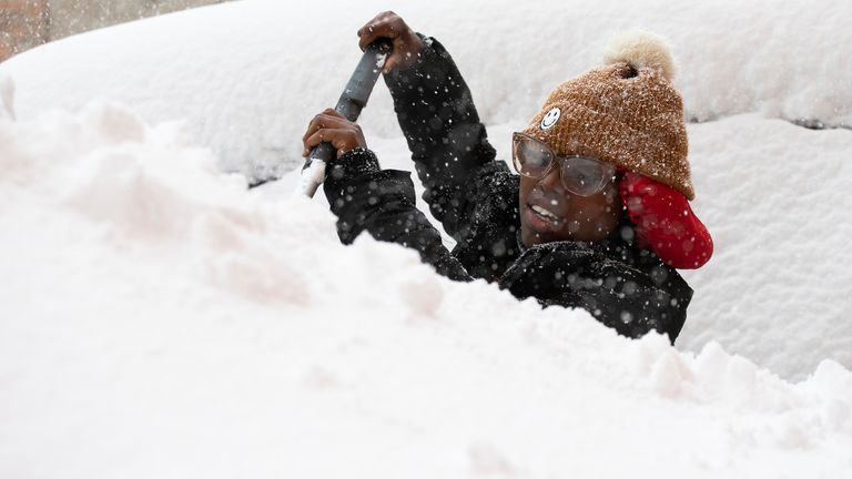 Zaria Black, 24, from Buffalo, clears off her car as snow falls  in Buffalo
PIC:AP