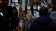 People wearing masks cross a street in Shanghai, China.