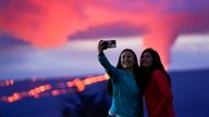 Ingrid Yang, left, and Kelly Bruno, both of San Diego, take a photo in front of lava erupting from Hawaii&#39;s Mauna Loa volcano Wednesday, Nov. 30, 2022, near Hilo, Hawaii. (AP Photo/Gregory Bull)