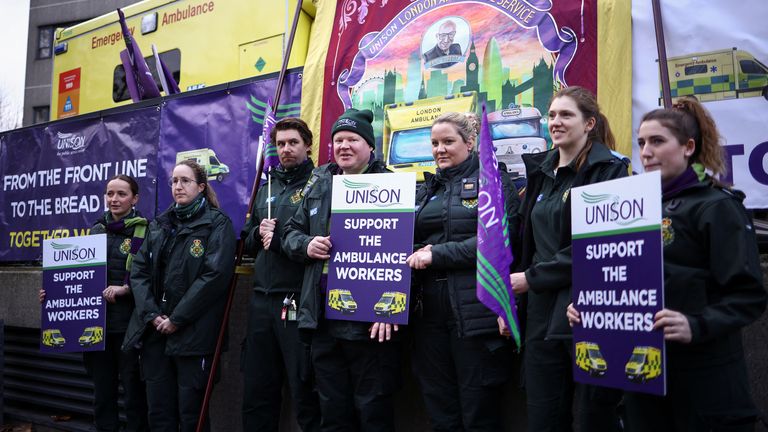 Ambulance workers hold signs as they take part in a strike, amid a dispute with the government over pay, outside the London NHS Ambulance Service in London. 