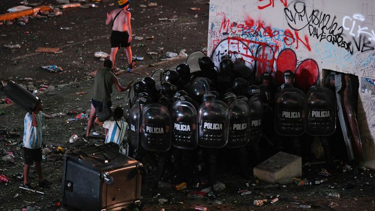 Police form a phalanx during clashes with remaining soccer fans who waited for hours for a homecoming parade for the players who won the World Cup at the Obelisk in Buenos Aires, Argentina, Tuesday, Dec. 20, 2022. A parade to celebrate the champions was abruptly cut short Tuesday as millions of people poured onto thoroughfares, highways and overpasses in a chaotic attempt to catch a glimpse of the national team. (AP Photo/Gustavo Garello)