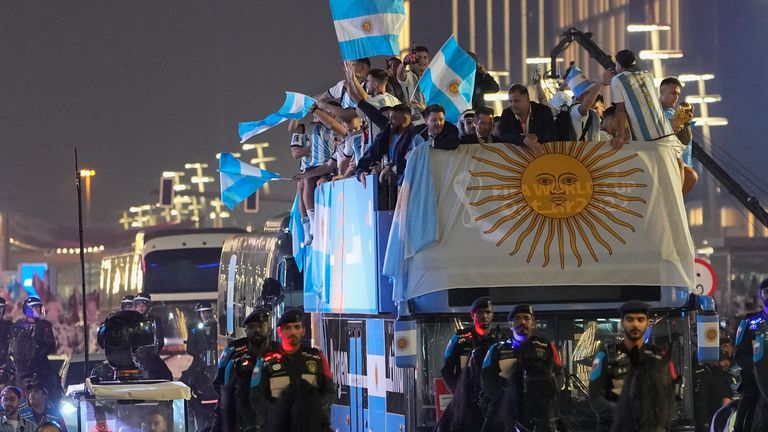 A bus with the celebrating Argentina players, who wave to their fans, travels from the Lusail Stadium after they won the World Cup Final defeating France on penalties, in Lusail, Qatar, Monday, Dec. 19, 2022. (AP Photo/Andre Penner)