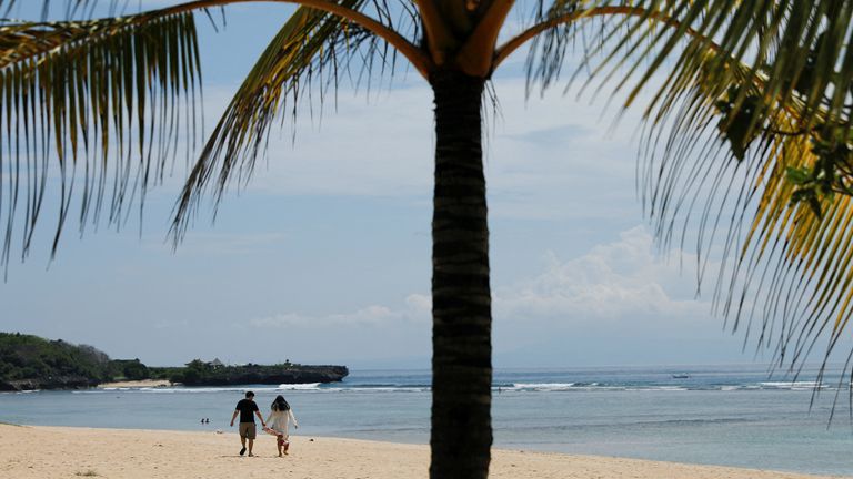 A couple walk along the beach in Bali.