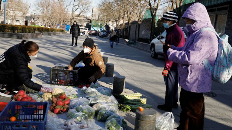 People shop for vegetables at a street stall in Beijing