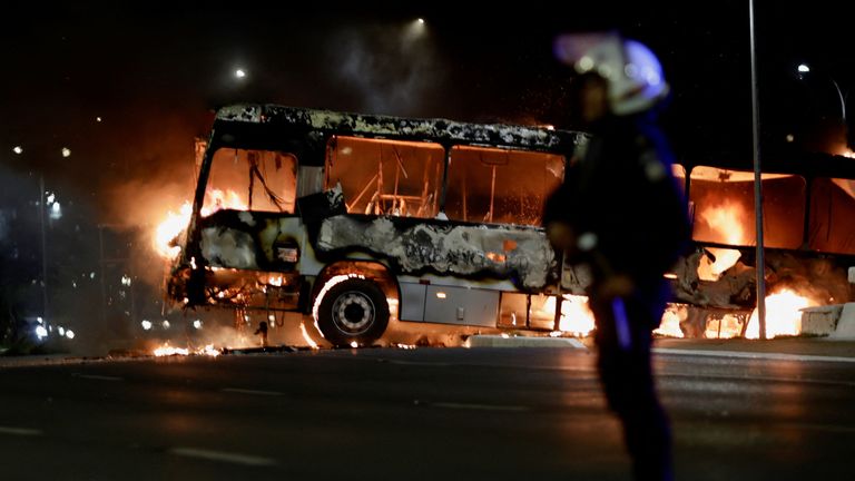 A police officer stands near a bus on fire as supporters of Brazil&#39;s President Jair Bolsonaro protest after supreme court justice Alexandre de Moraes ordered a temporary arrest warrant of indigenous leader Jose Acacio Serere Xavante for alleged anti-democratic acts, in Brasilia, Brazil