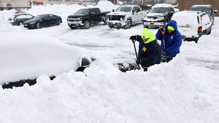 People work to dig out a car during a winter storm that hit the Buffalo region, in Amherst, New York, U.S., December 26, 2022. REUTERS/Brendan McDermid