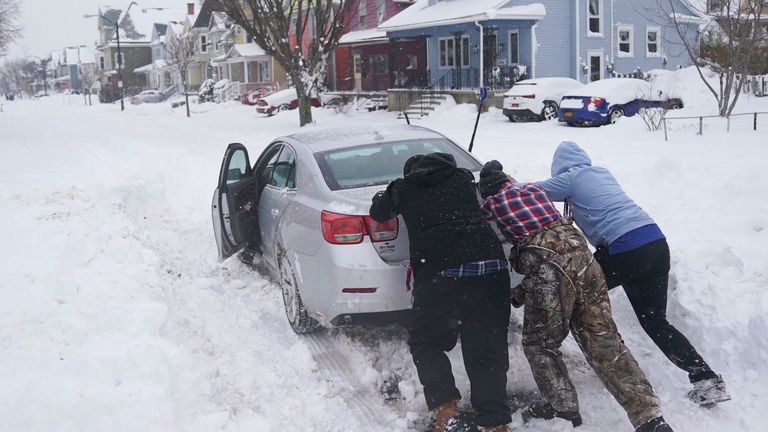 Neighbors help push a motorist stuck in the snow in Buffalo, N.Y., on Monday, Dec. 26, 2022. (Derek Gee/The Buffalo News via AP)