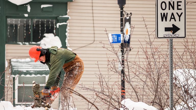 A man uses a chainsaw to remove a fallen tree blocking a road after a winter storm in Buffalo, New York, U.S., December 27, 2022. REUTERS/Lindsay DeDario