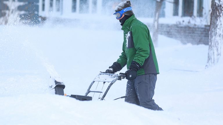 A man clears snow from his driveway following a winter storm that hit the Buffalo area in Amherst, New York, U.S., December 25, 2022.