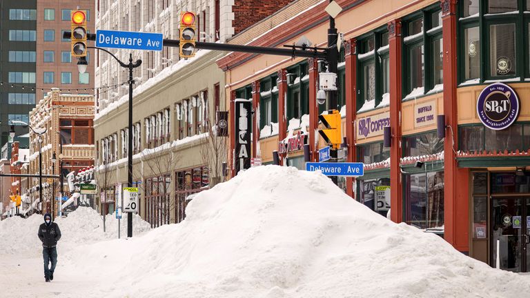 A man walks next to a snowdrift formed by a plow after a winter storm in Buffalo, New York, U.S., on December 27, 2022.REUTERS/Lindsay DeDario