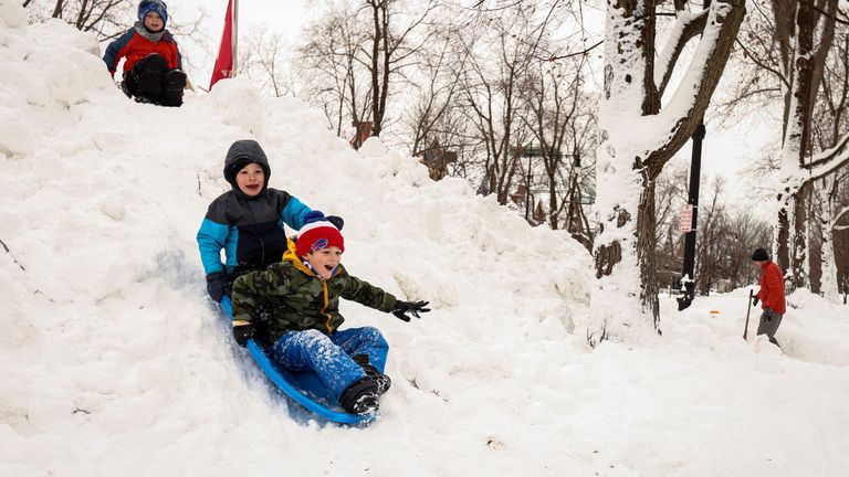 Perry (6) and Theo (6) sled down snow pile formed by a snow plow following a winter storm in Buffalo, New York, U.S., December 27, 2022.  REUTERS/Lindsay DeDario