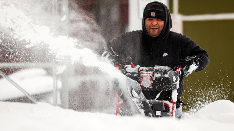 A man uses a snow blower to remove snow from the sidewalk following a winter storm in Buffalo, New York, U.S., December 27, 2022.  REUTERS/Lindsay DeDario