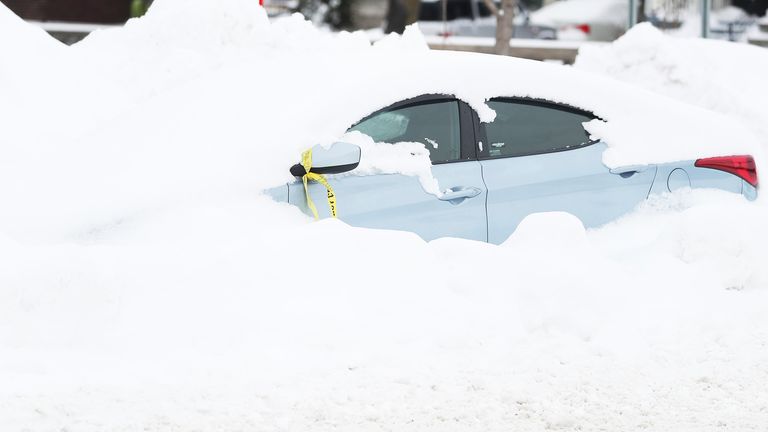 An abandoned car is covered in snow on a street in Buffalo, N.Y., Tuesday, Dec. 27, 2022, days after a snowstorm hit four counties in western New York.  (Joseph Cook/AP Buffalo News)