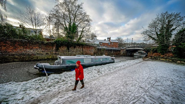 A woman walks through the frozen Bridgewater Canal in Lymm, Cheshire.  Snow and ice have swept across parts of the UK, with cold wintry conditions set to continue for days.  Drawing date: Friday December 16, 2022.