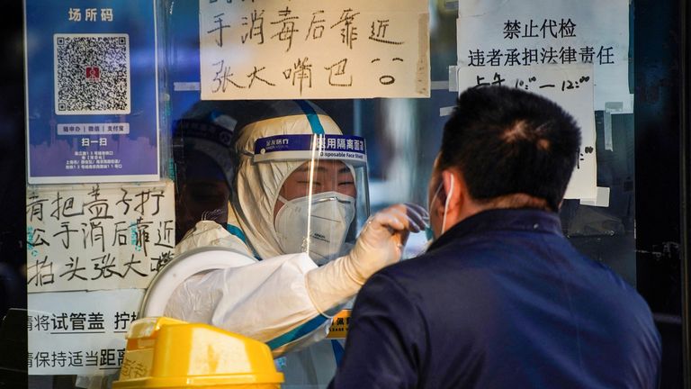 A medical worker in a protective suit collects a swab sample from a man at a nucleic acid testing site, as coronavirus disease (COVID-19) outbreaks continue in Shanghai, China, December 12, 2022. REUTERS/Aly Song