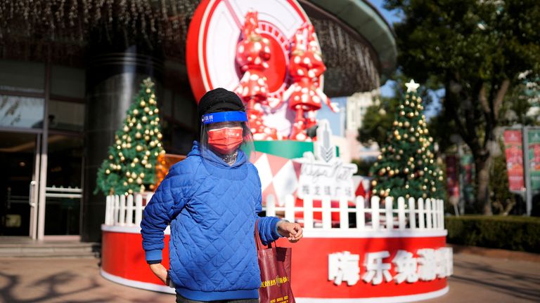 A woman wearing a face mask and face shield walks past a Christmas tree outside a shopping mall, as coronavirus disease (COVID-19) outbreaks continue in Shanghai, China, 