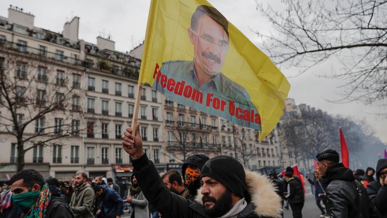 A Kurdish activist waves a flag with the face of imprisoned Kurdistan workers'  Party, or PKK, leader Abdullah Ocalan during a protest against the recent shooting at the Kurdish Culture Center in Paris, Saturday, Dec. 24, 2022. Kurdish activists, left-wing politicians and anti-racist groups are staging a protest Saturday in Paris after that three people were killed in a Kurdish cultural center in an attack targeting foreigners.  (AP Photo/Lewis Joly)