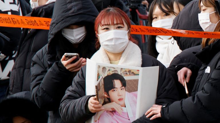 A fan holding a picture waits for the arrival of Jin, the oldest member of the K-pop band BTS, outside a South Korean army boot camp near the demilitarized zone separating the two Koreas, in Yeoncheon, South Korea December 13, 2022. REUTERS/Heo Ran
