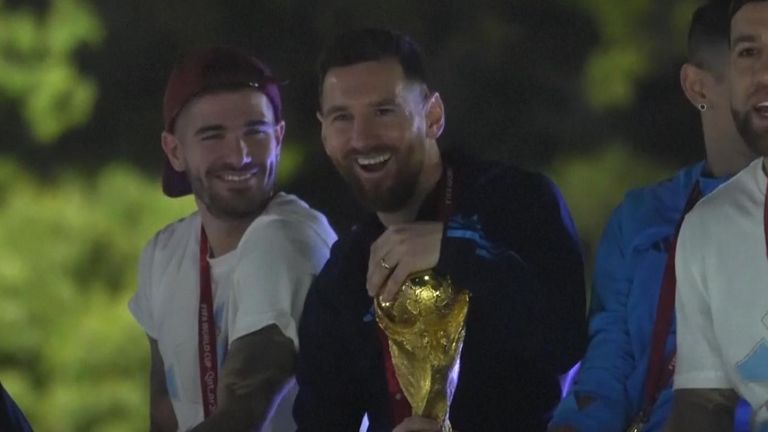 Lionel Messi smiles as he holds the World Cup trophy
