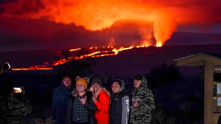 People pose for a photo in front of lava erupting from Hawaii&#39;s Mauna Loa volcano Wednesday, Nov. 30, 2022, near Hilo, Hawaii. 
PIC:AP