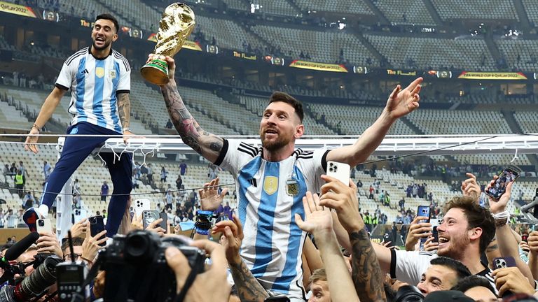 Argentina's Lionel Messi celebrates with fans and teammates after receiving the World Cup trophy