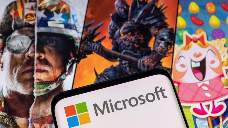 Microsoft logo is seen on a smartphone placed on displayed Activision Blizzard&#39;s games characters