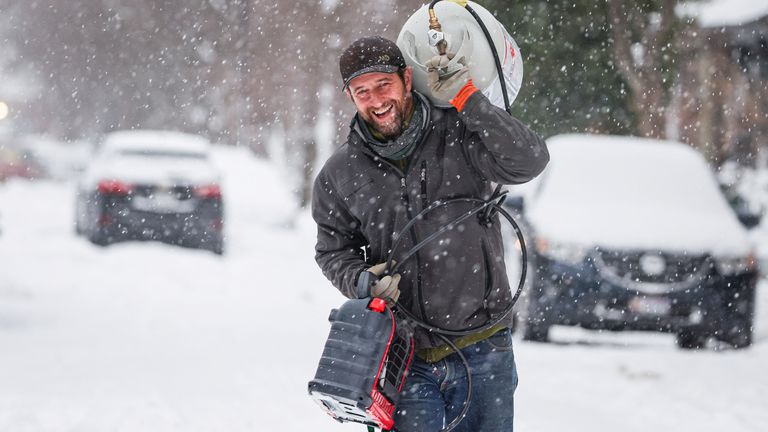 A man brings a propane tank and heater to a friend after a winter storm in Buffalo, New York 