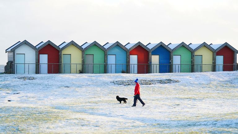 Dog walkers near the beach huts on Blyth beach, Northumberland, on the north east coast. Snow and ice have swept across parts of the UK, with cold wintry conditions set to continue for days. Picture date: Wednesday December 14, 2022. 