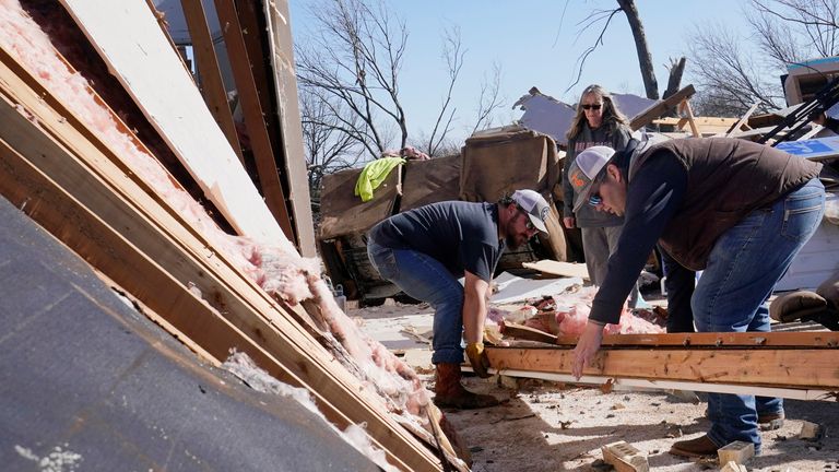 Belinda Penner  watches  Jr. Ibarra, and Jared Reaves carry a beam from her cousin&#39;s tornado destroyed home in Oklahoma
Pic:AP