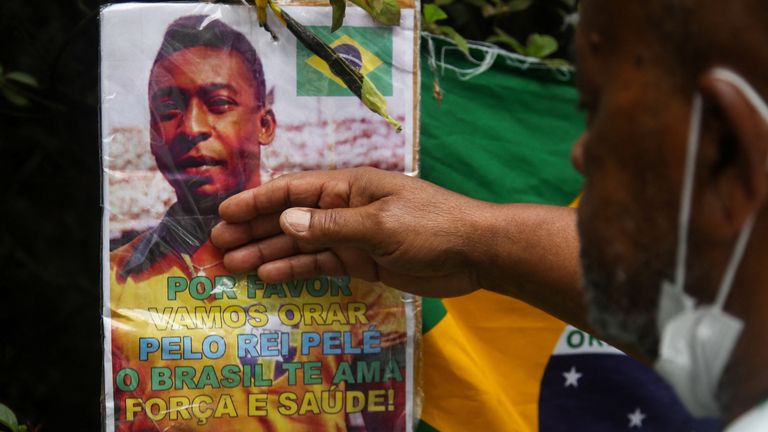 Renato Souza, a fan of Brazilian soccer legend Pele touches a placard outside the hospital as people mourn his death, in Sao Paulo, Brazil, December 30, 2022. REUTERS/Carla Carniel