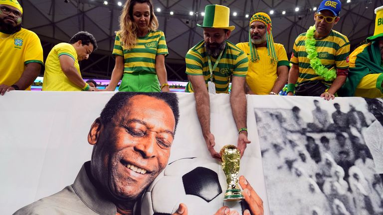 A Brazil fan holds a replica World Cup trophy over a picture of former player Pele ahead of the FIFA World Cup Group G match at the Lusail Stadium in Lusail, Qatar. Picture date: Friday December 2, 2022.
