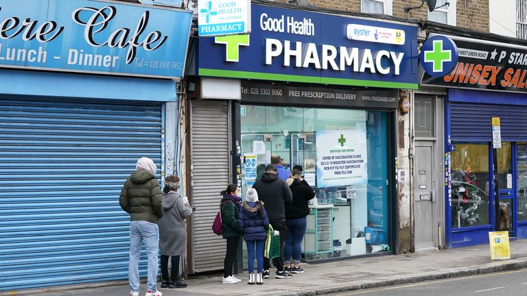 People wait in line to receive a 'Jingle Jab' Covid vaccination booster shot at Good Health Pharmacy, north London