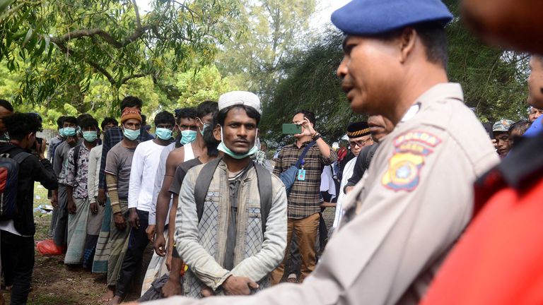 A policeman guards Rohingya refugees after they arrived at a beach in Ladong village, Aceh province, Indonesia, December 25, 2022, in this photo taken by Antara Foto.  Antara Foto/Ampelsa/via REUTERS ATTENTION EDITORS - THIS IMAGE WAS PROVIDED BY A THIRD PARTY.  COMPULSORY CREDIT.  INDONESIA OUT.  NO COMMERCIAL OR EDITORIAL SALE IN INDONESIA.