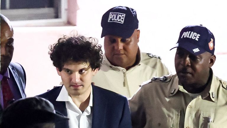 Sam Bankman-Fried, who founded and led FTX until a liquidity crunch forced the cryptocurrency exchange to declare bankruptcy, is escorted out of the Magistrate Court building after his arrest in Nassau, Bahamas December 13, 2022. REUTERS/Dante Carrer REFILE - CORRECTING INFORMATION