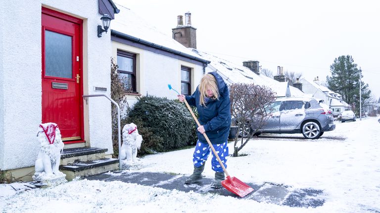 A resident in Carlops in the Scottish Borders clears snow from the pavement. 