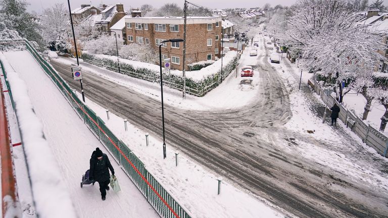 A woman pulls a shopping trolley in a snow covered residential area in Leytonstone, London. Pic: AP