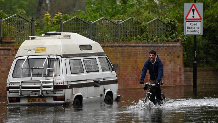 A man cycles through flood water as the River Thames floods at high tide on a Springtide in London, Britain, April 28, 2021. REUTERS/Toby Melville
