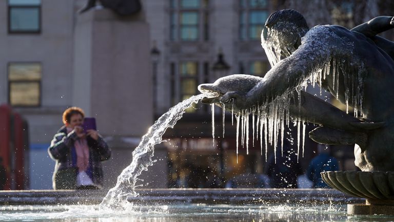 A man takes a picture of a standing fountain in Trafalgar Square, central London.  Snow and ice have swept across parts of the UK, with cold wintry conditions set to continue for days.  Drawing date: Friday December 16, 2022.