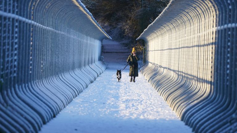 A woman walks her dog through snow over Castleside Viaduct in Durham. Parts of the UK are being hit by freezing conditions with the UK Health Security Agency (UKHSA) issuing a Level 3 cold weather alert covering England until Monday and the Met Office issuing several yellow weather warnings for snow and ice in parts of the UK over the coming days. Picture date: Friday December 9, 2022.
