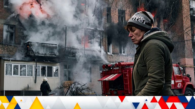 A woman walks past her burning house after Russian shelling in Bakhmut. Pic: AP