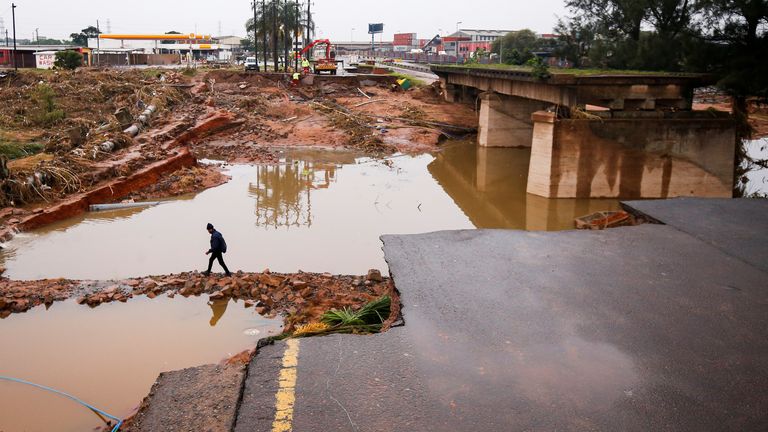 A man walks around a damaged bridge caused by flooding in Umlazi near Durban, South Africa, April 16, 2022. REUTERS/Rogan Ward