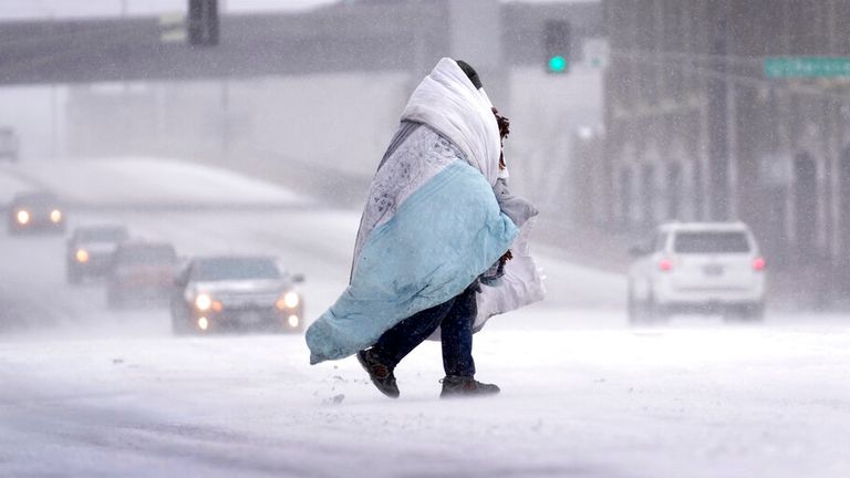 A person wrapped in a blanket crosses a snow-covered street in St. Louis in the middle of a bomb cyclone.  Image: AP