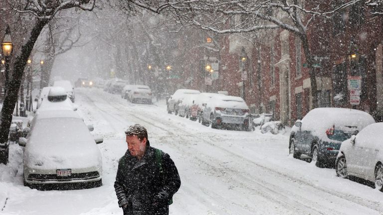 A pedestrian walks through falling snow during a winter storm in Boston, Massachusetts