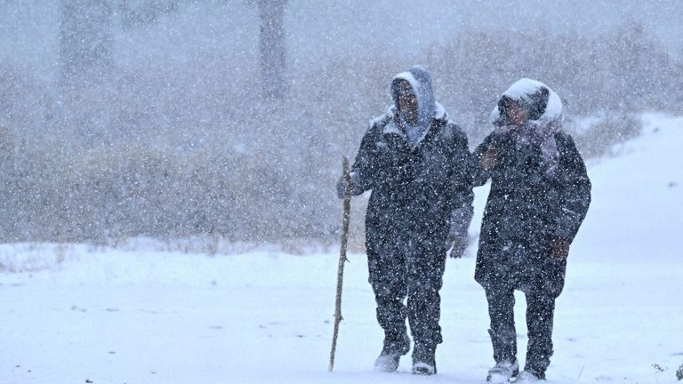 Wrightwood residents Nick and Christine Hoban enjoy a walk together as heavy snow falls on Highway 2 near Wrightwood, California  
PIC:AP
