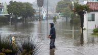 A man wades through a flooded street in the Rio Del Mar neighborhood of Aptos, California. Pic: AP