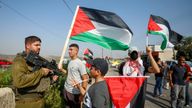 Demonstrators hold Palestinian flags in front of an Israeli soldier in Qalqilya in the Israeli-occupied West Bank