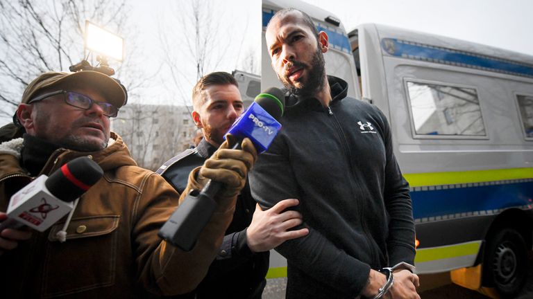 Police officers escort Andrew Tate past the Organized Crime and Terrorism Investigation Directorate (DIICOT) where prosecutors are examining electronic material confiscated during the investigation into their case, in Bucharest, Romania PIC: AP