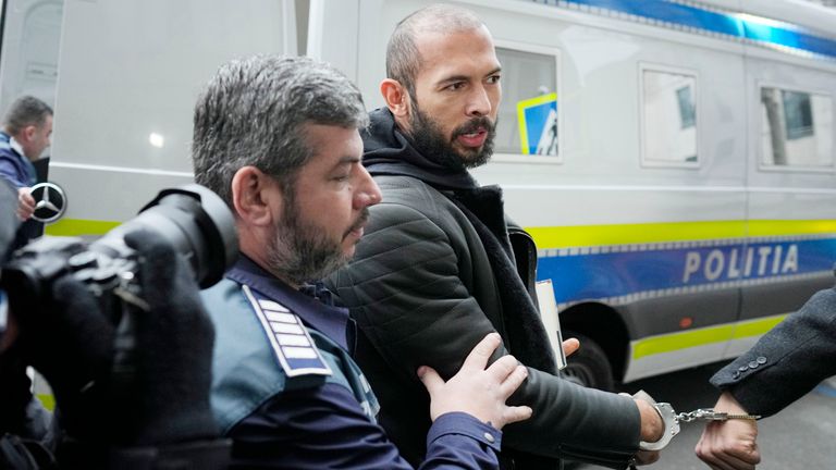 Police officers escort Andrew Tate handcuffed to his brother Tristan outside the Directorate for Investigating Organized Crime and Terrorism (DIICOT) where prosecutors examine electronic equipment confiscated during the investigation in their case, in Bucharest, Romania 
Pic:AP